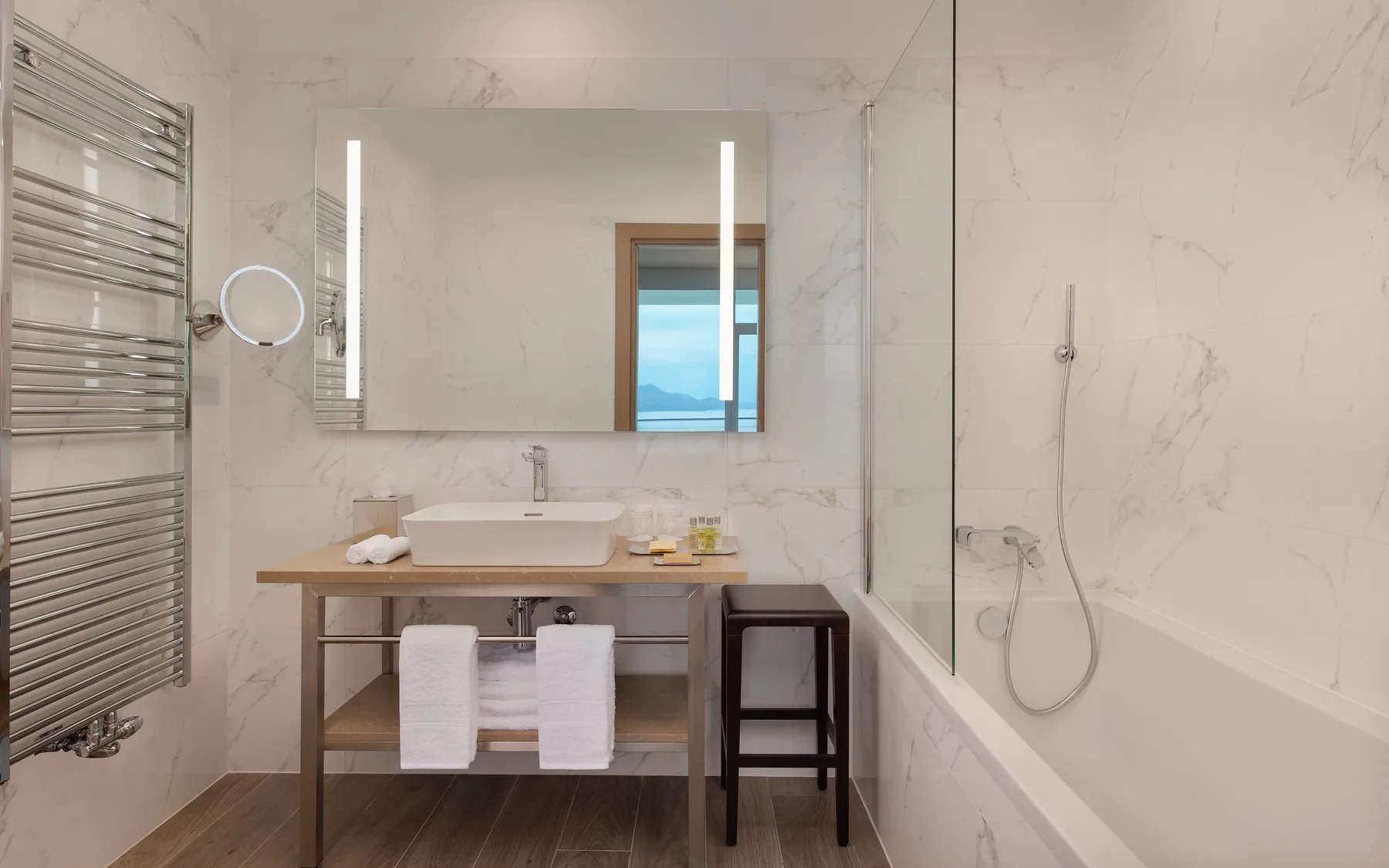 Bagno di una suite con rivestimenti in marmo chiaro e top del lavabo in pietra
