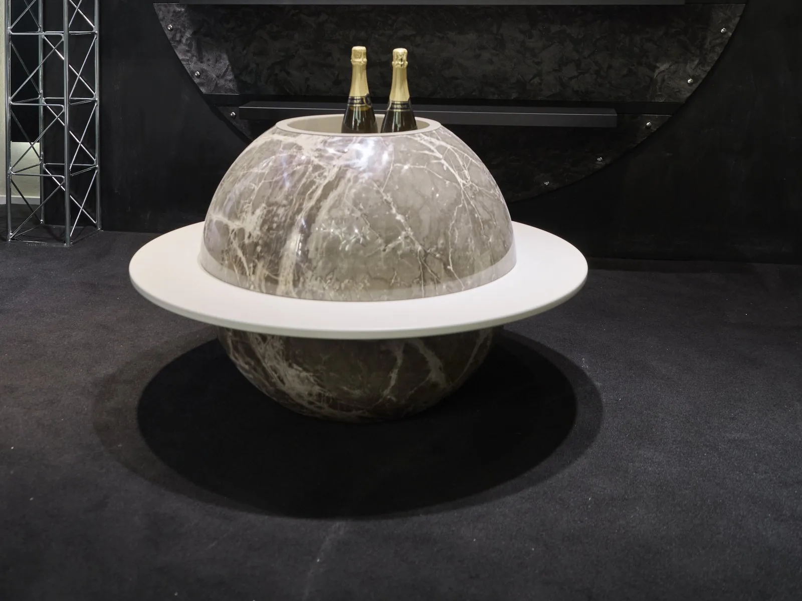 Mobile bar Parione: sfera in marmo grigio venato con anello bianco passante, la calotta aperta scopre il vano per le bottiglie